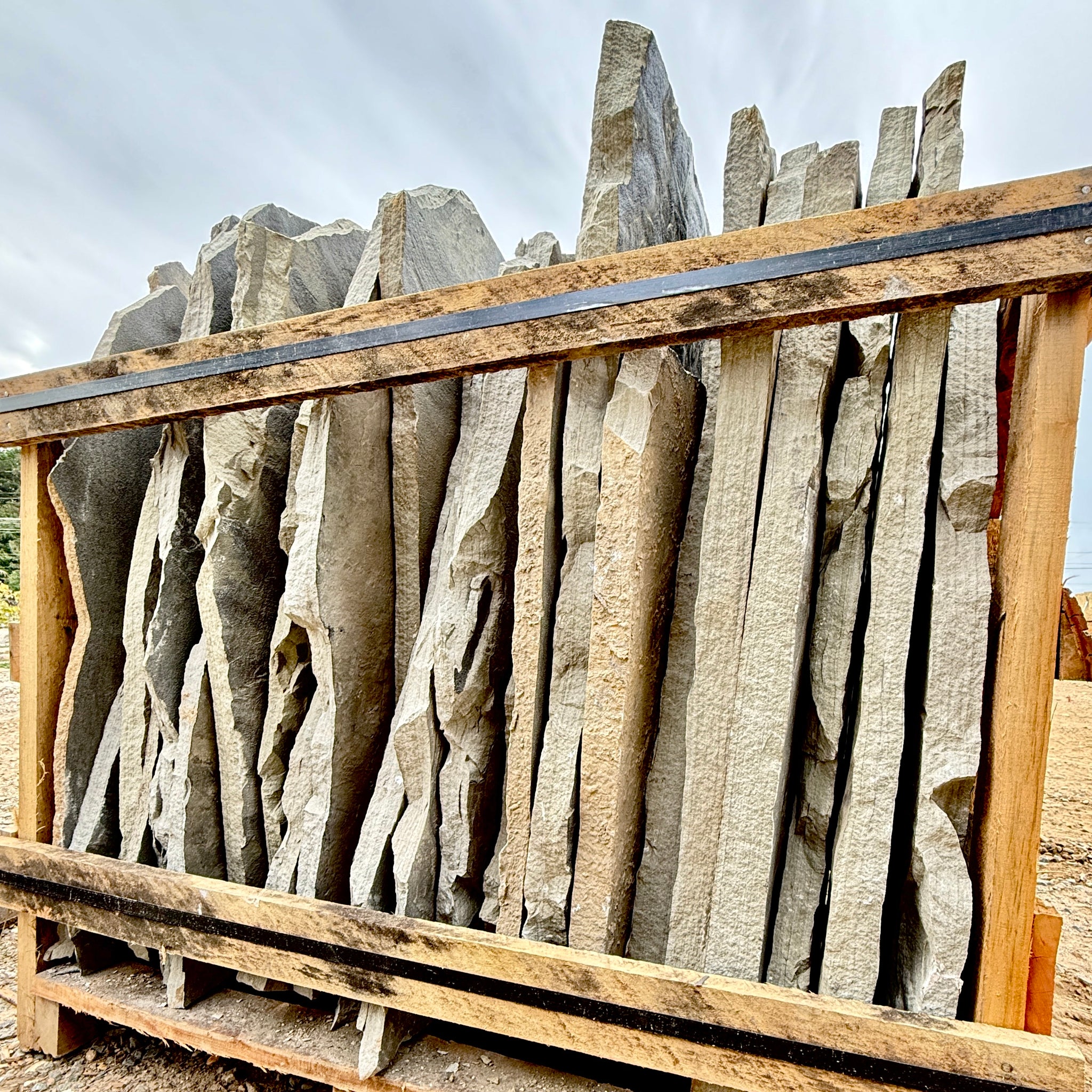 Stack of stone slabs with wooden frame against a cloudy sky