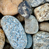 Close-up of Newport River Rounds 1–3 inch showing smooth rounded stones in natural gray, tan, brown, and cream tones.