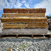 Rock Island Lilac stone steps on a 2,000 lb pallet, stacked face-out to show rust-gold cleft edges against a blue sky