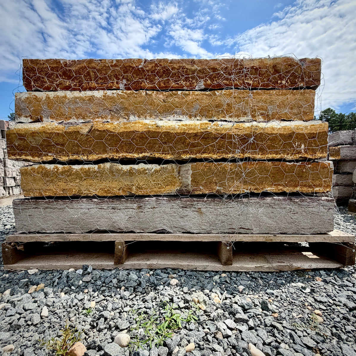 Rock Island Lilac stone steps on a 2,000 lb pallet, stacked face-out to show rust-gold cleft edges against a blue sky