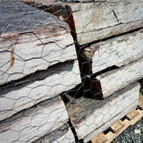 Pallet of Rock Island Lilac natural stone steps wrapped in wire, showing gray layered faces and rust-colored sides