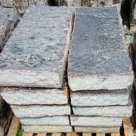 Rock Island Lilac stone steps on a 2,000 lb pallet, stacked face-out to show rust-gold cleft edges against a blue sky