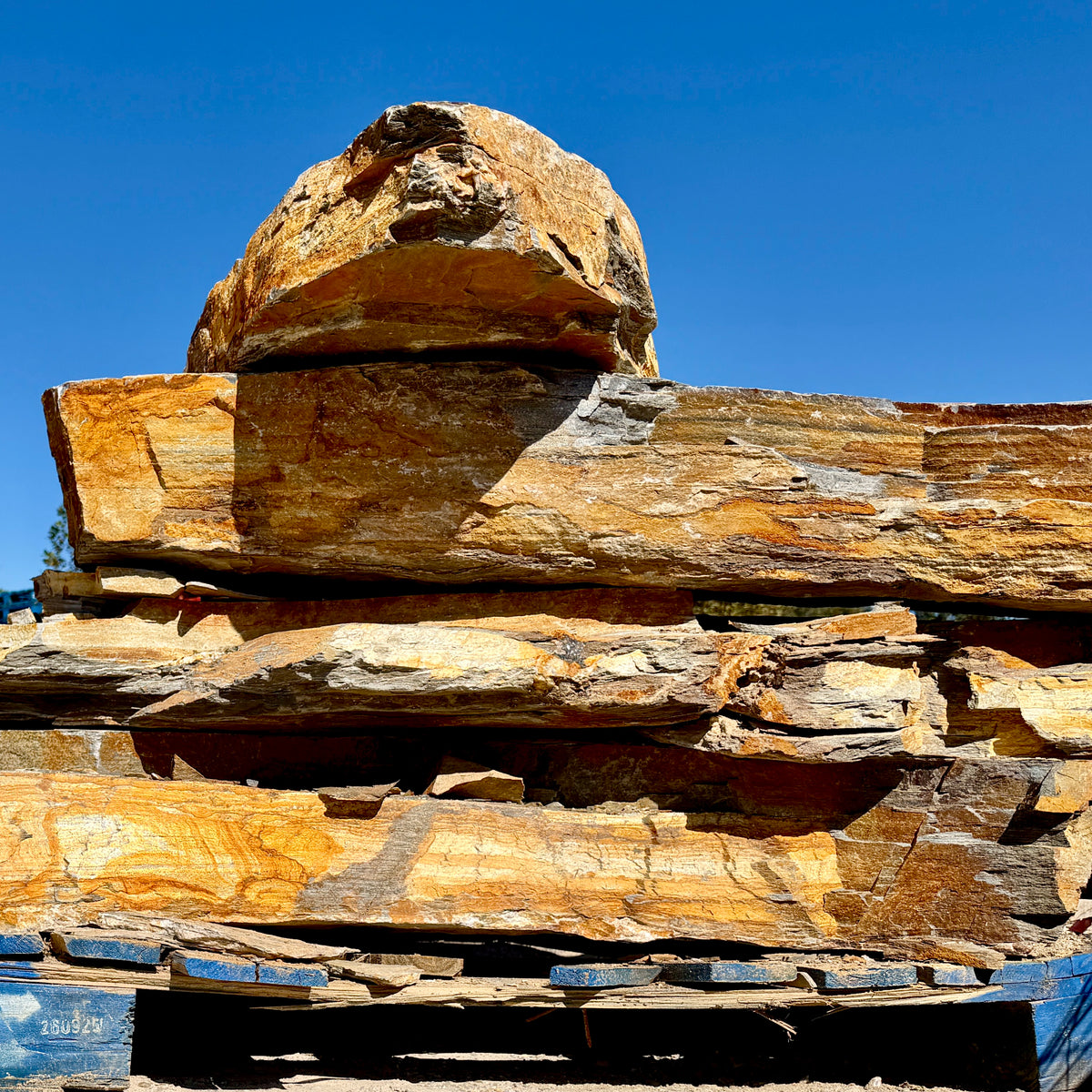 Side view of stacked Summer Tan granite landscape steps showing thick stone profiles and naturally textured edges.