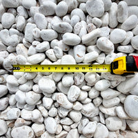 Close-up of smooth White Mexican Beach Pebbles with naturally polished surfaces and a measuring tape for reference